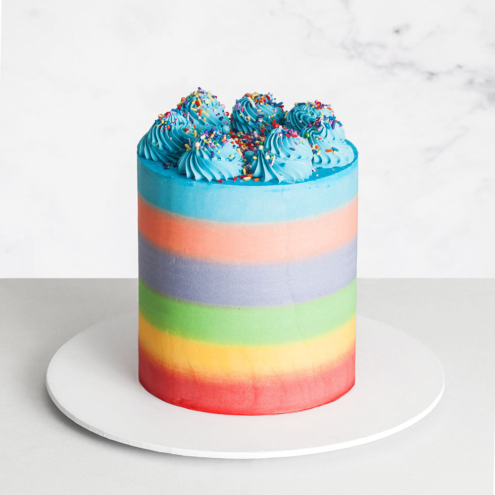 Rainbow buttercream cake with piping and sprinkles