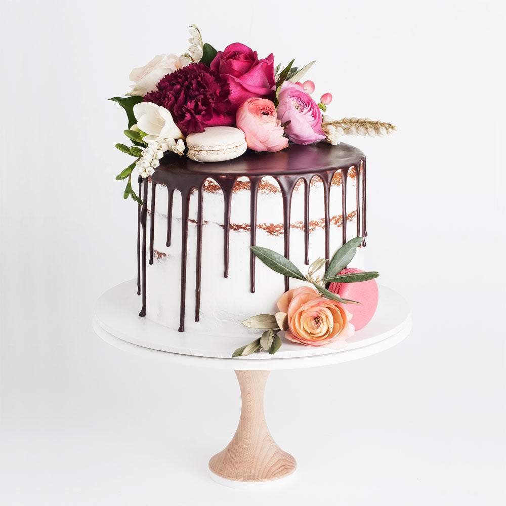 Natural semi-naked cake with dark chocolate drip, macarons and flowers